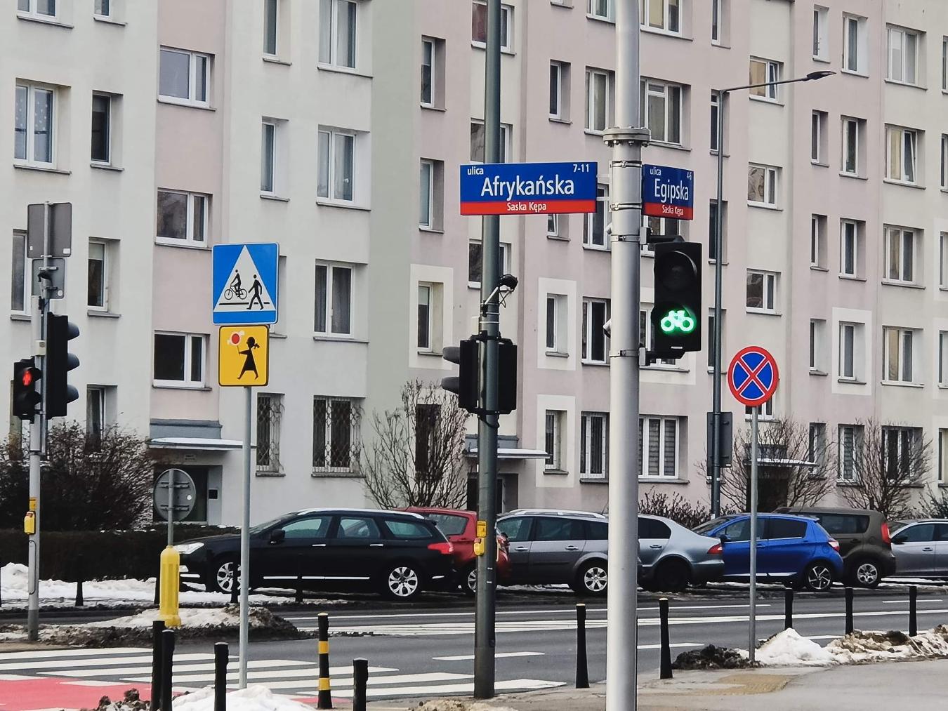 Widok na ulicę Warszawy: skrzyżowanie ulic Afrikanska i Egipaska, sygnalizacja świetlna, przejście dla pieszych i zaparkowane samochody.