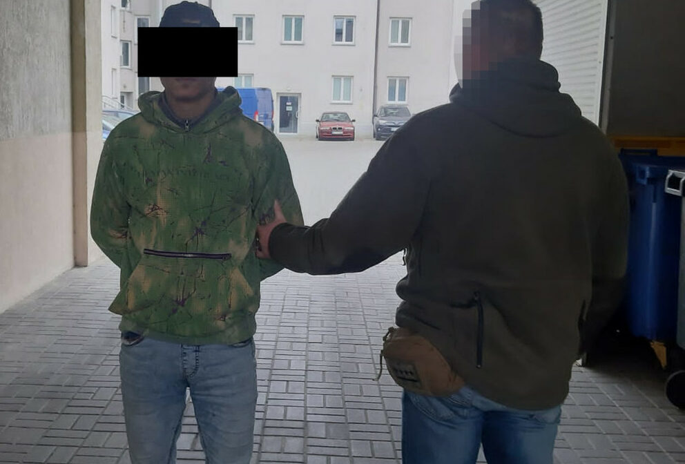 Policjant aresztujący podejrzanego w zaułku.