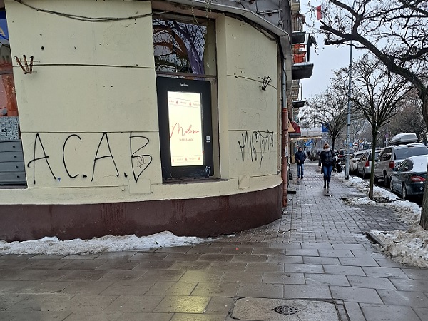 Graffiti z napisem „ACAB” na ścianie budynku w pobliżu chodnika.