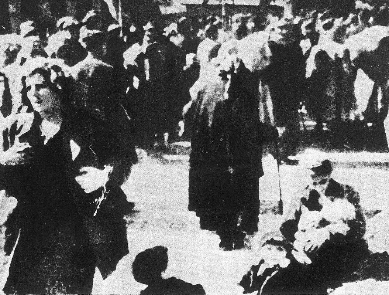 Czarno-białe zdjęcie tłumu podczas protestu, przedstawiające ludzi ubranych w stroje z epoki.