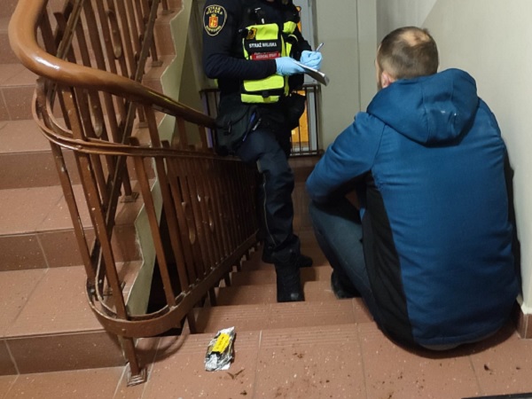 Policjant przesłuchujący podejrzanego na schodach.