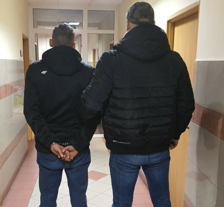 Dwóch mężczyzn w kajdankach idących korytarzem