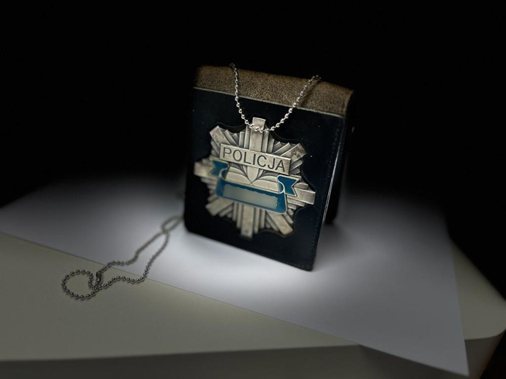 Odznaka policyjna z napisem „POLICJA” na skórzanym uchwycie i łańcuszku.