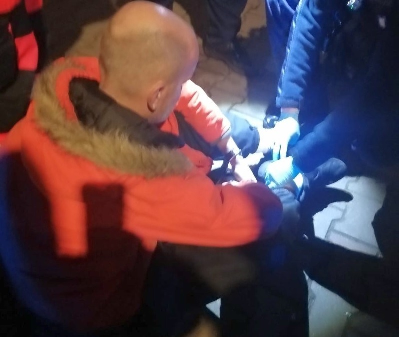 Ratownicy udzielają w nocy pomocy nodze rannej osobie.