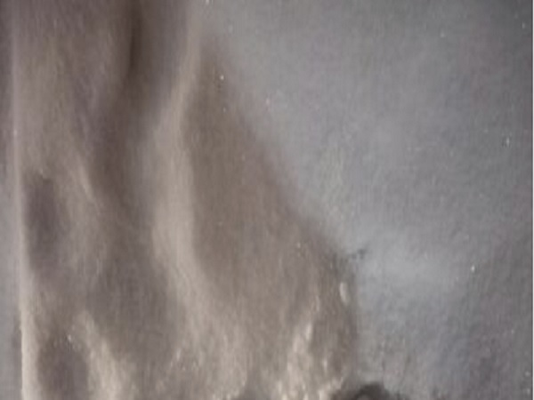 Zbliżenie drobnego, jasnoszarego proszku, prawdopodobnie talku lub innej podobnej substancji.