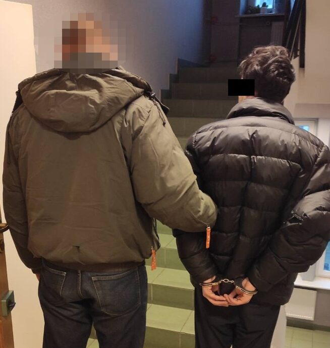 Policjant aresztujący podejrzanego w kajdankach.