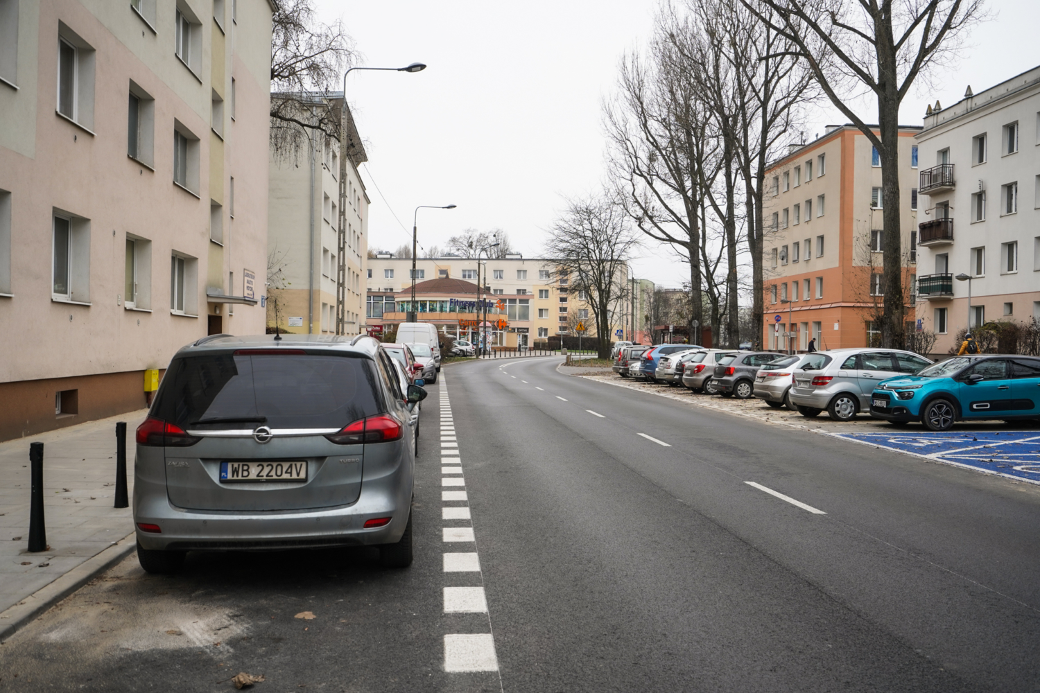 Samochody zaparkowane na ulicy mieszkalnej w Polsce. Widoczna tablica rejestracyjna WB 2204V.
