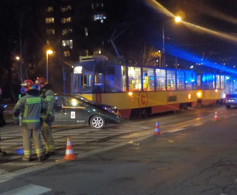 Strażacy na miejscu zdarzenia w nocy po zderzeniu tramwaju z samochodem.