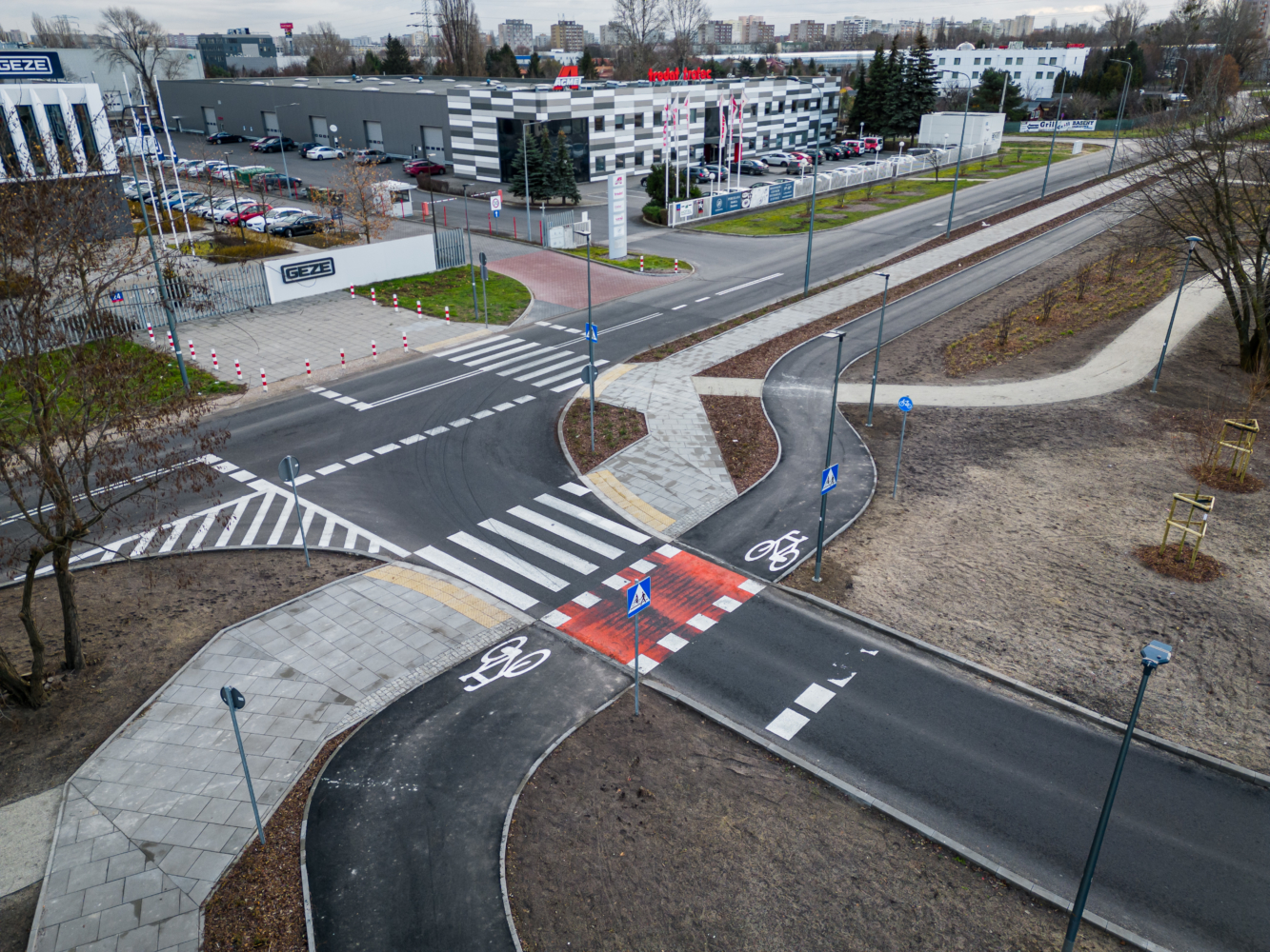 Widok z lotu ptaka na nowoczesne skrzyżowanie ze ścieżkami rowerowymi i przejściami dla pieszych.