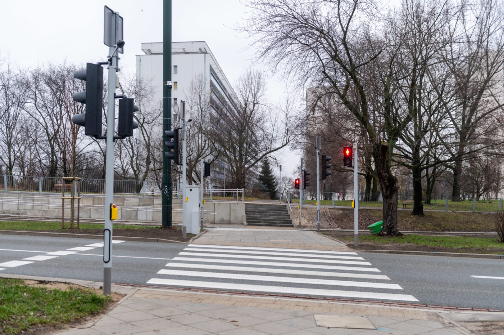 Przejście dla pieszych ze światłami włączonymi na czerwono, w pobliżu budynków mieszkalnych.