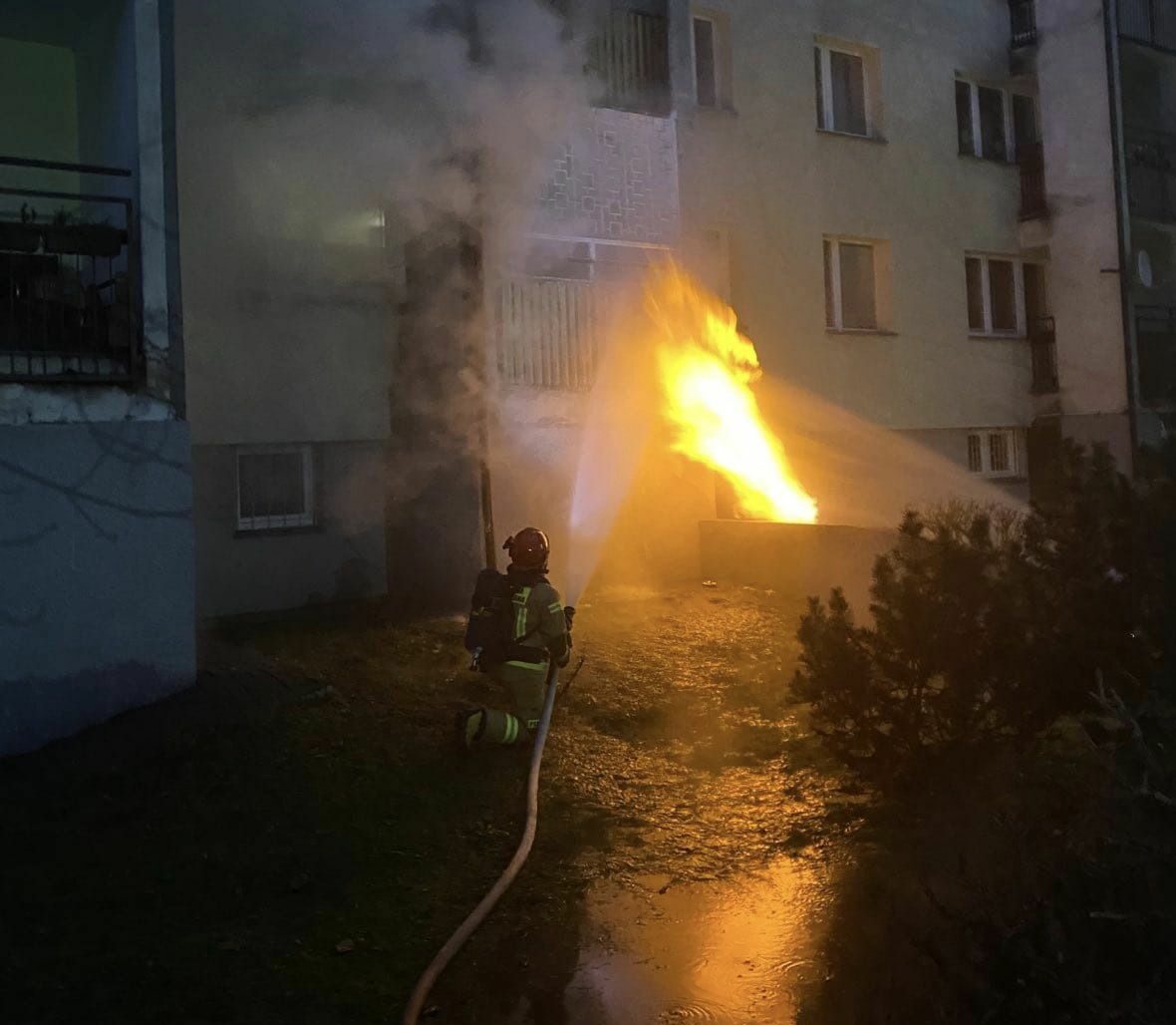 Strażak gasi nocą pożar budynku mieszkalnego