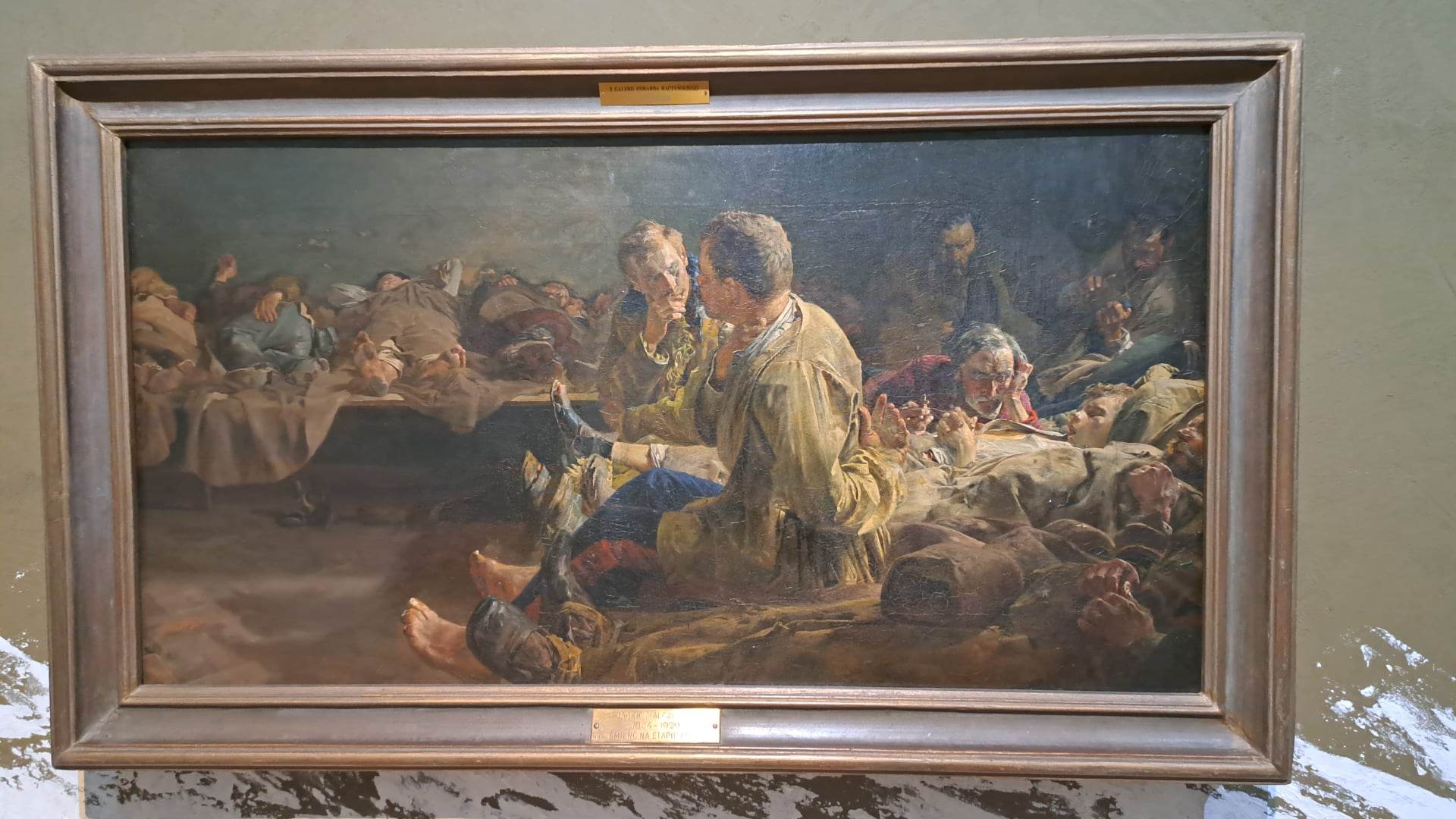 Żołnierze odpoczywają w słabo oświetlonym pomieszczeniu, niektórzy śpią, inni rozmawiają.