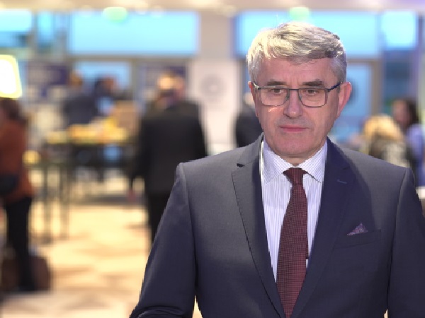 Portret mężczyzny w garniturze i okularach na konferencji biznesowej.