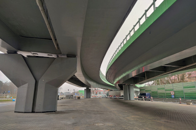 Nowoczesny wiadukt autostradowy z zakrzywionymi rampami i betonowymi podporami.