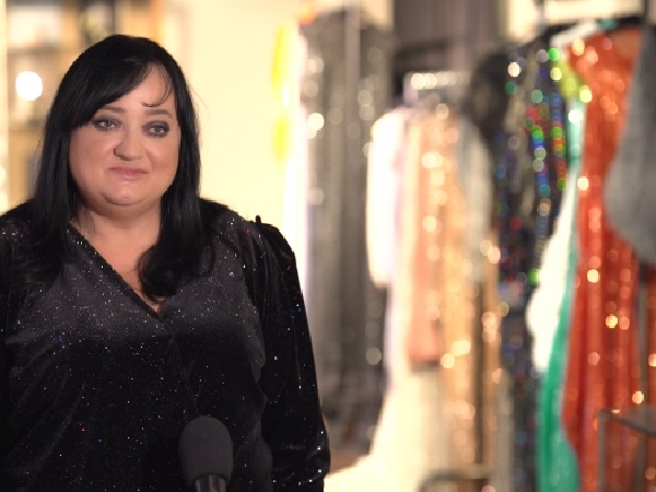 Kobieta w czarnej błyszczącej sukience mówiąca do mikrofonu