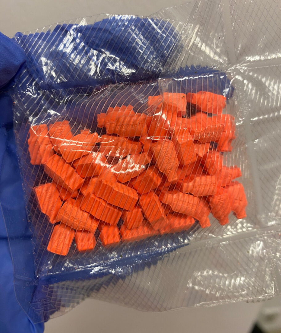 Zbliżenie na paczkę pomarańczowych tabletek fentanylu zarekwirowaną przez organy ścigania.