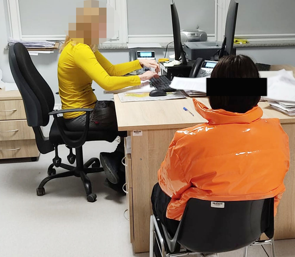Dwie kobiety pracujące przy biurkach, jedna siedzi na wózku inwalidzkim.