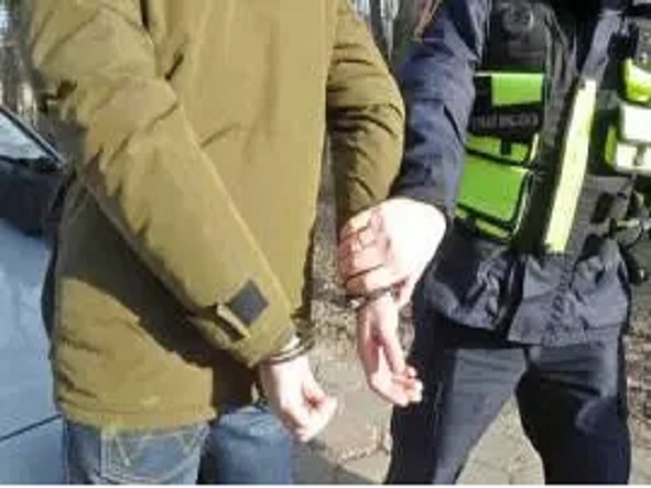 Policjant aresztujący podejrzanego za pomocą kajdanek