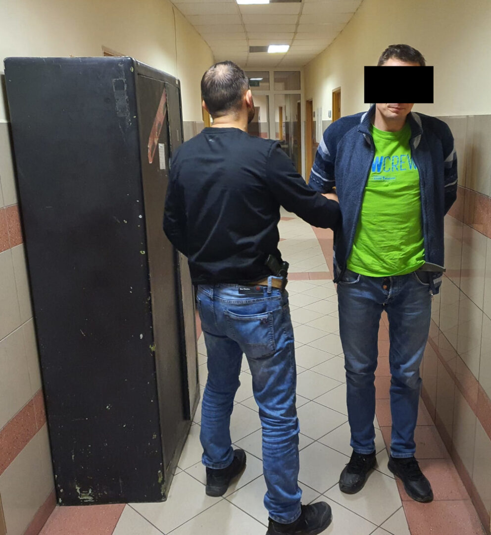 Policjant aresztujący podejrzanego na korytarzu, w pobliżu dużej metalowej szafy