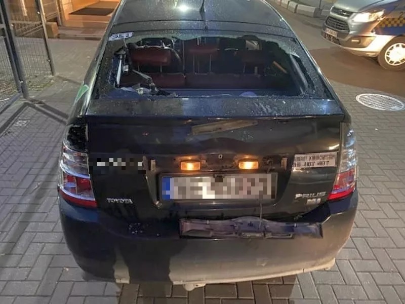 Widok z tyłu uszkodzonego czarnego samochodu Toyota Prius z rozbitą tylną szybą.