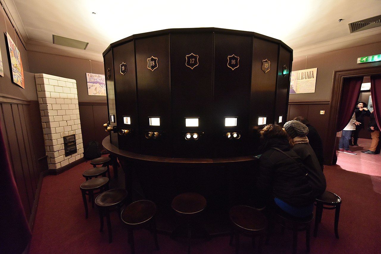 Zwiedzający oglądają obrazy stereoskopowe na urządzeniu z początku XX wieku.