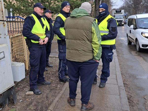 Policjanci rozmawiają z mężczyzną na ulicy miasta.