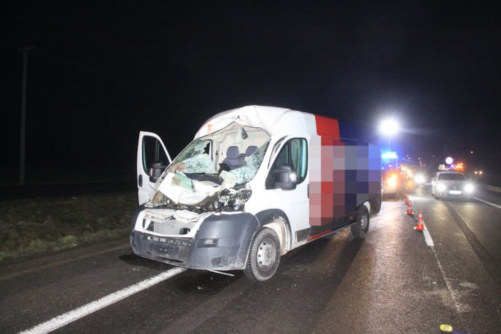 Uszkodzony biały van po wypadku samochodowym na autostradzie w nocy.