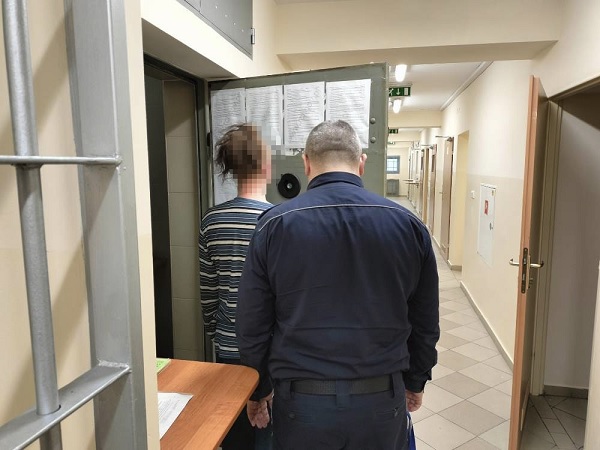 Więzień eskortowany przez strażnika korytarzem