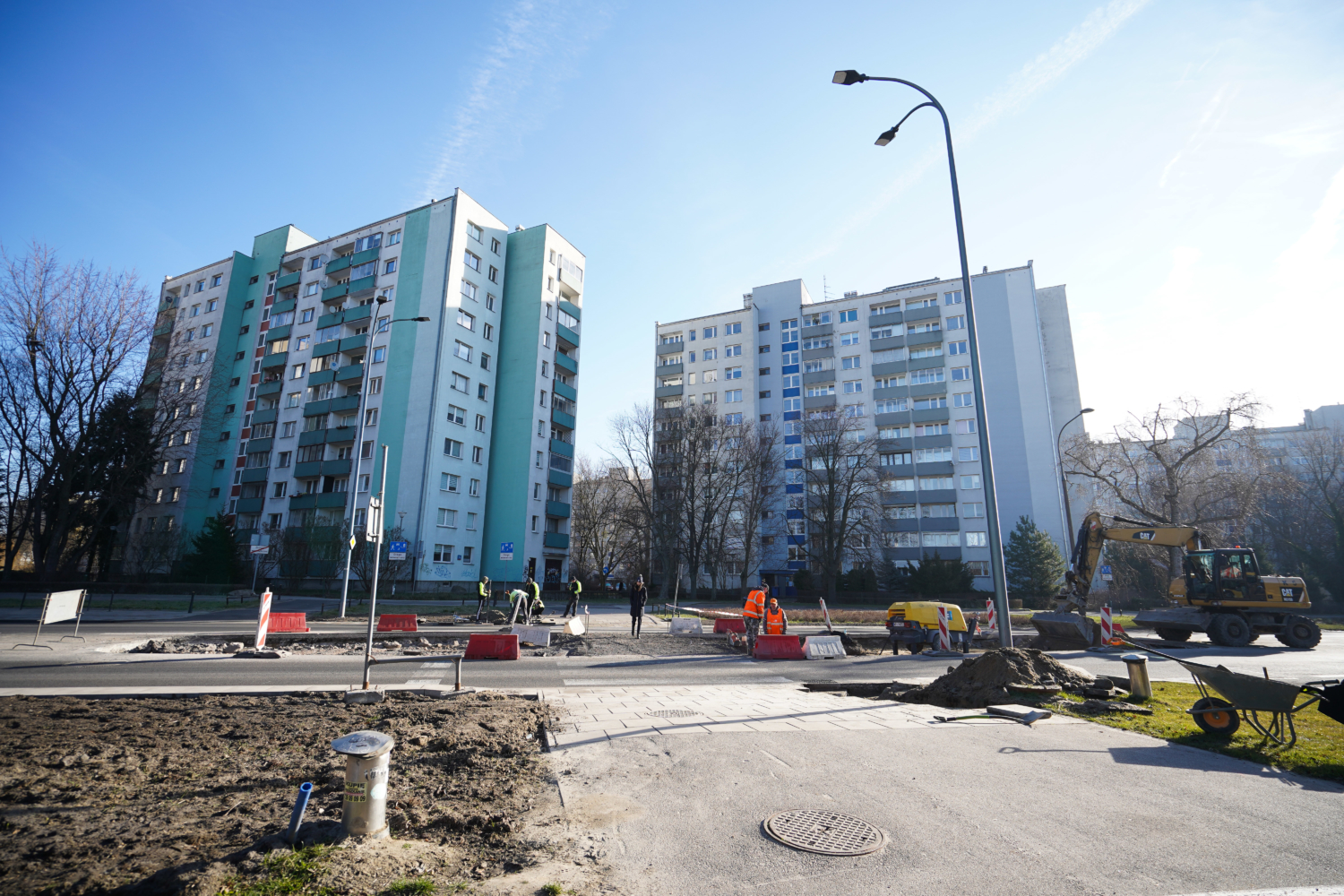 Robotnicy drogowi w pobliżu budynków mieszkalnych.