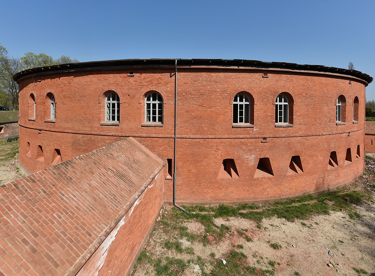 Ceglany okrągły fort z łukowatymi oknami i otworami strzelniczymi