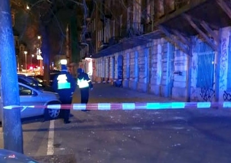 Policjanci badają nocą miejsce zbrodni oznaczone taśmą policyjną.