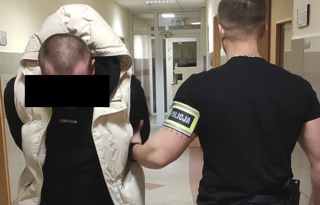 Policjant aresztujący podejrzanego z rękami skutymi z tyłu.