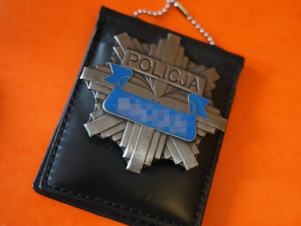 Odznaka policyjna z napisem „POLICJA” w czarnym skórzanym etui.