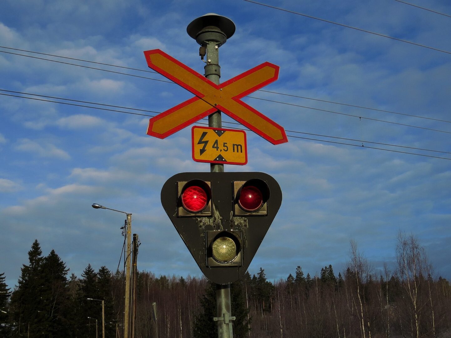 Szlaban na przejazd kolejowy z czerwonymi i żółtymi sygnałami, ostrzeżenie o wysokości 4,5 m.