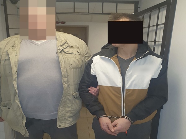 Dwóch mężczyzn w kajdankach, jeden w beżowej kurtce, drugi w kurtce w bloki kolorów. Aresztowanie.