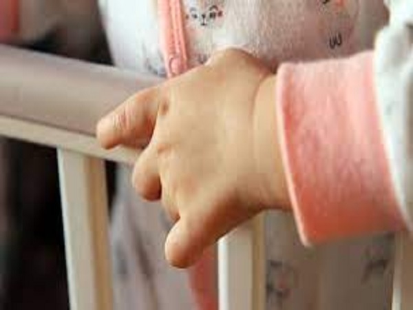 Ręką dziecka chwytająca barierkę łóżeczka