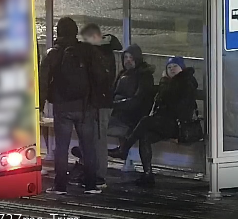 Cztery osoby czekające na przystanku autobusowym zimą.