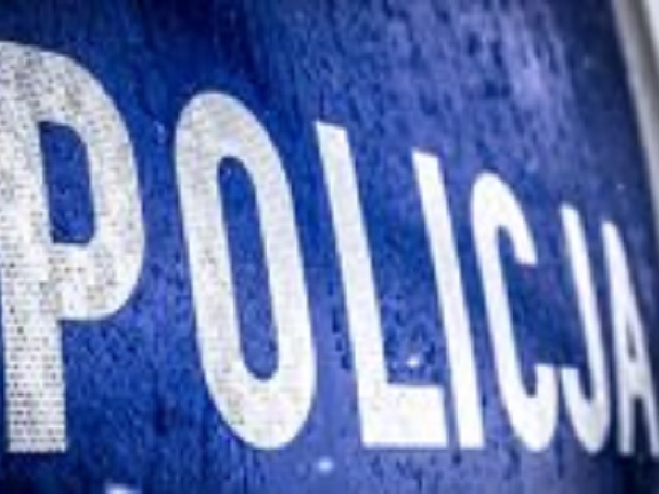 Zbliżenie na drzwi radiowozu z napisem „POLICJA” wykonanym białymi literami.