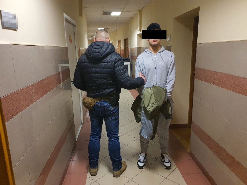 Policjant eskortujący podejrzanego korytarzem