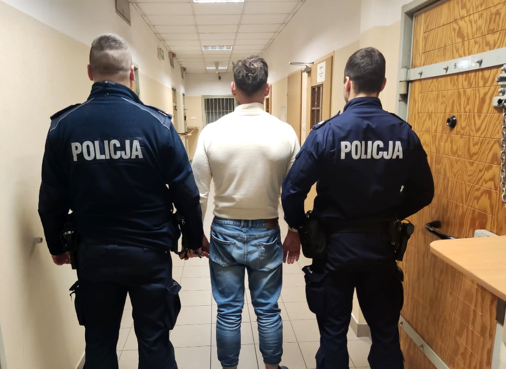 Dwóch polskich policjantów eskortuje podejrzanego korytarzem więziennym. POLICJA