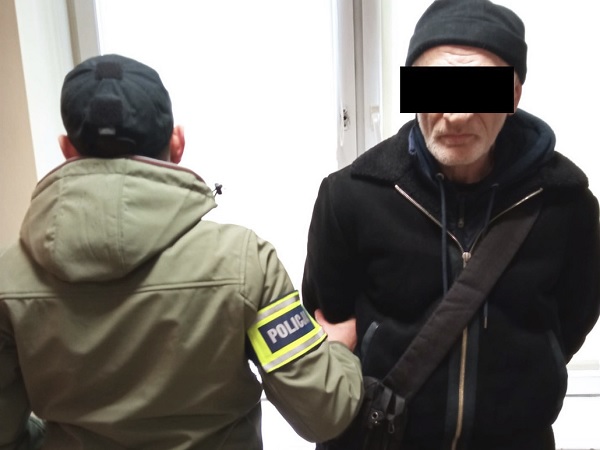 Policjant aresztujący mężczyznę. Widoczna opaska POLICJI.