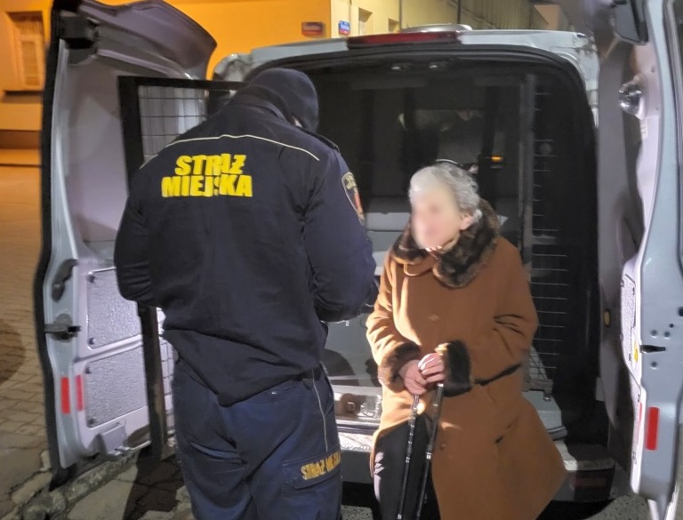 Strażnik miejski pomaga starszej kobiecie wejść do furgonetki