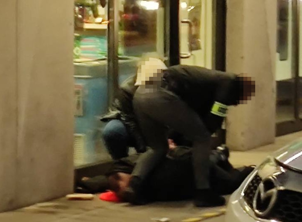 Policjanci obezwładniają podejrzanego leżącego na ziemi.