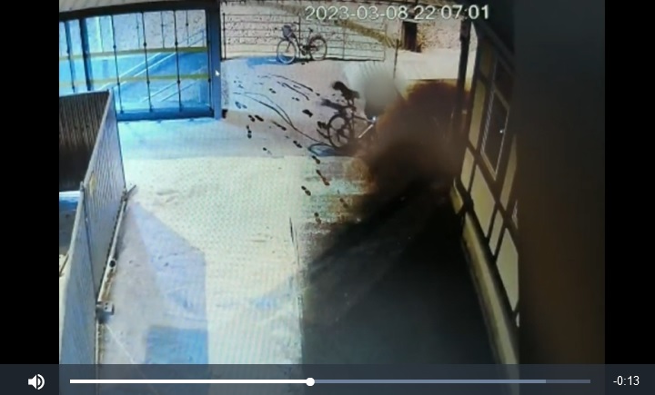 Nagrania z kamer pokazują mężczyznę jadącego nocą na rowerze w pobliżu wejścia do budynku.