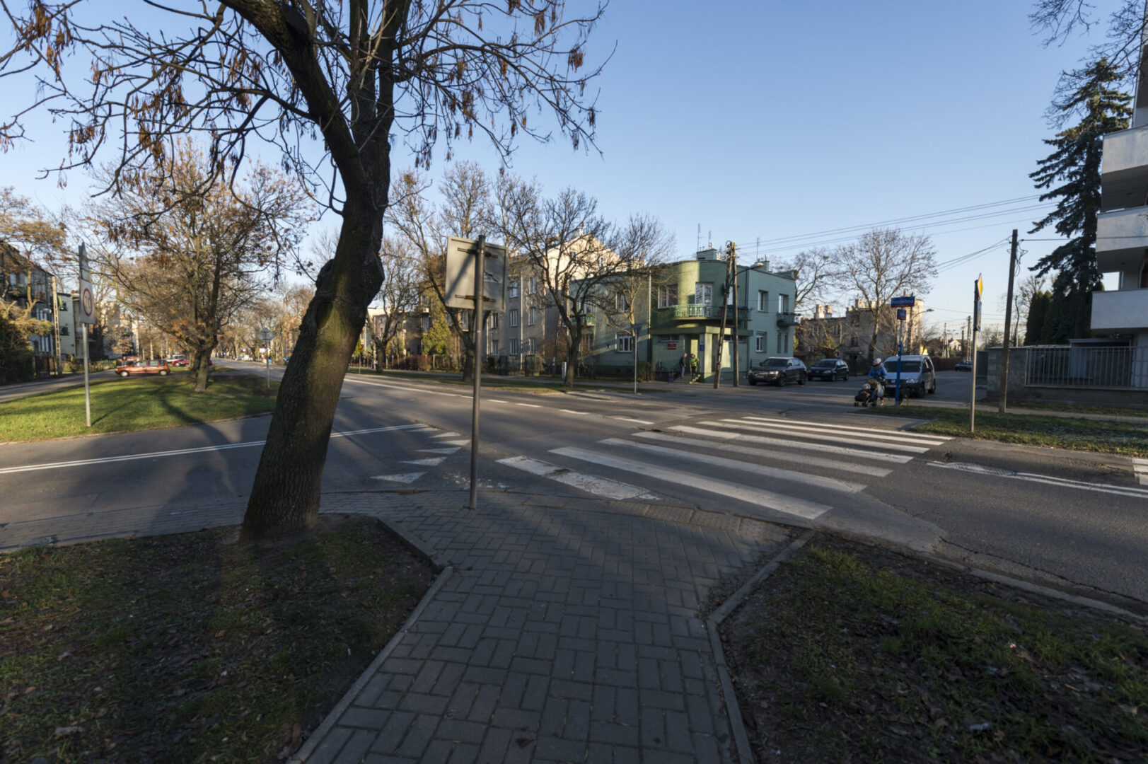 Przejście dla pieszych na terenie mieszkalnym z drzewami i budynkami.