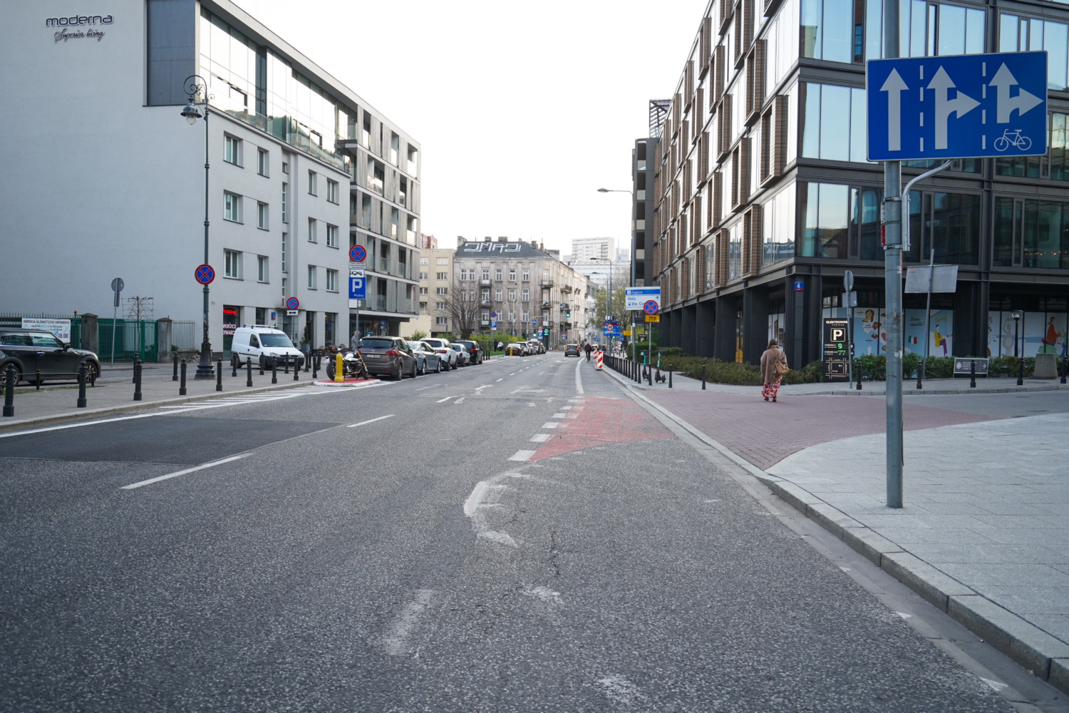 Pusta ulica miasta z nowoczesnymi budynkami i zaparkowanymi samochodami.