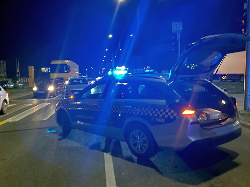 Radiowóz policyjny w nocy z otwartym bagażnikiem, widoczny numer 986.