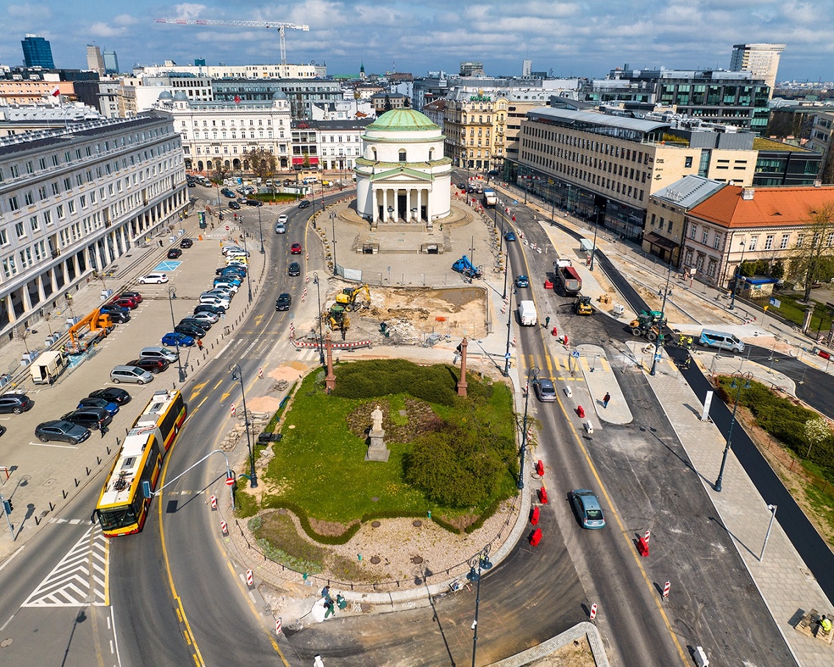 Widok lotniczy zrewitalizowanego Placu Grzybowskiego w Warszawie, ukazujący nowe układy dróg i zagospodarowanie terenu wokół zabytkowego kościoła.