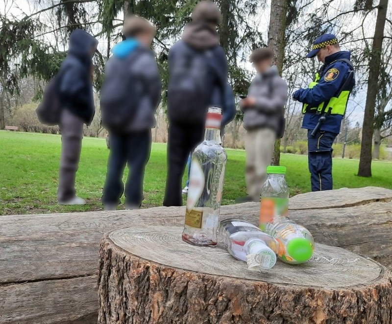 Policjant znajduje porzucony alkohol i napoje w pobliżu nastolatków w parku.
