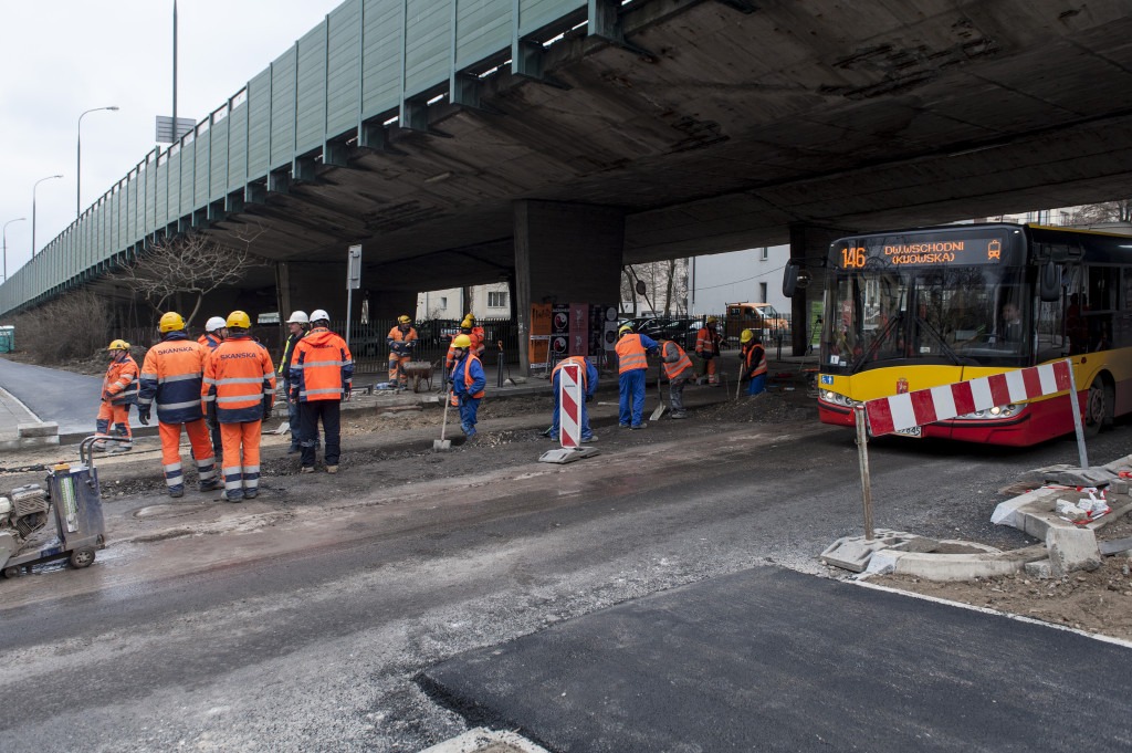 Ekipa drogowa naprawiająca asfalt pod wiaduktem autostradowym. Widoczny autobus nr 146.